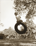 photograph of boy on tire swing